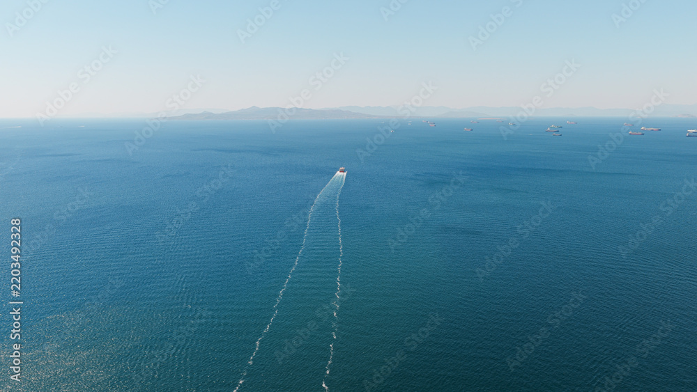 Fototapeta premium Cargo ship navigating vast blue ocean creating wake