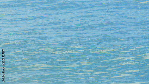 A tranquil blue  surface with gentle ripples and subtle sun reflections, idea...