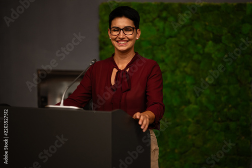 Cuadro en lienzo Businesswoman delivering a public presentation smiling confidently at podium