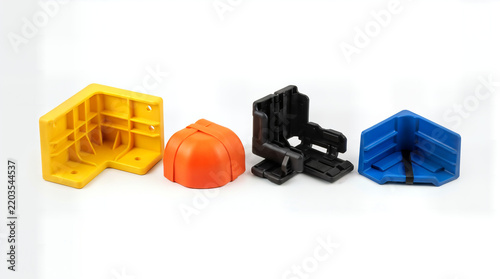 Colorful plastic corner protectors and safety parts lined up on a white surface