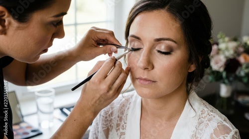 Professional makeup artist applying false eyelashes to bride