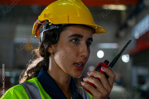 Close-up woman factory worker speaking on radio in warehouse