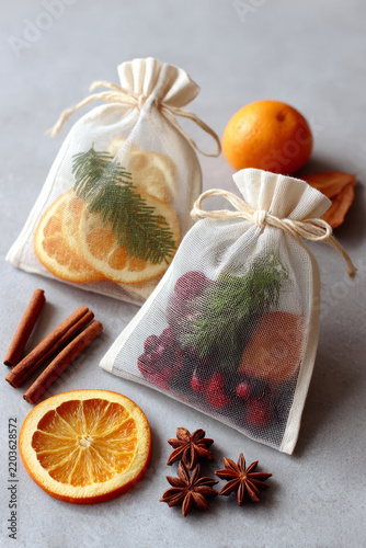 Dried citrus and spice sachets with cinnamon, star anise, orange, and evergreen botanicals on a gray tabletop still life
