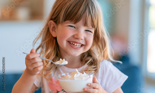 close-up of a young child happily eating yogurt with a spoon