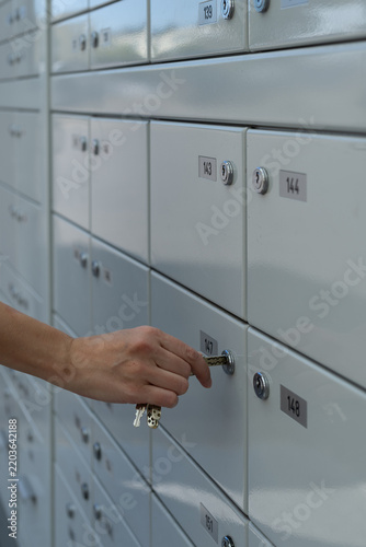 Fotografie A close-up photo of a female hand inserting a key into the lock of her post office box