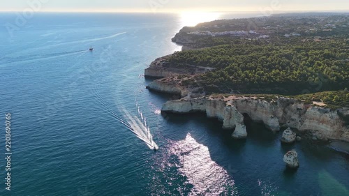 Amazing scenic drone aerial view of the beach and ocean with calm waves during a sunset with vibrant colors. Algarve, Portugal. Clear waters. Holidays and Vacations. Background. Beach with rocks. 