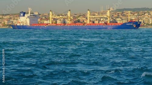 Large Blue Cargo Ship Sailing in the Bosphorus Strait with Istanbul Skyline and Mosque in Background