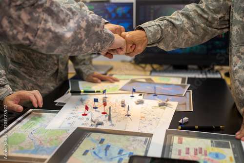 Experienced military hands focused intensely around a tactical map table, actively collaborating and planning precise strategic operations, operational logistics