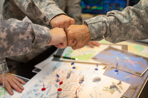 Experienced military hands focused intensely around a tactical map table, actively collaborating and planning precise strategic operations, operational logistics