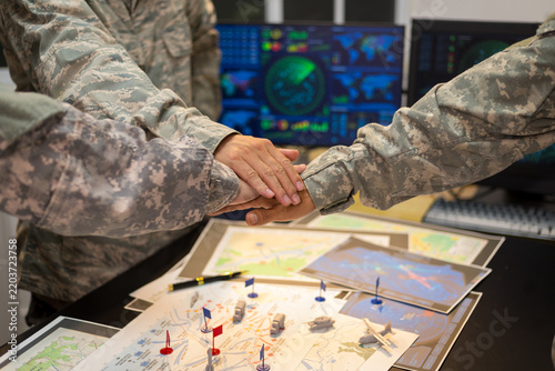 Experienced military hands focused intensely around a tactical map table, actively collaborating and planning precise strategic operations, operational logistics