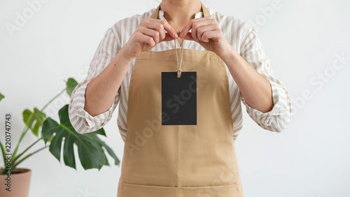 Small business owner in coffee shop wearing apron and holding blank dark chalkboard sign
