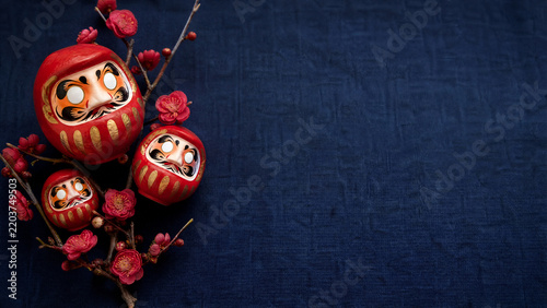 Red daruma dolls with plum blossoms for Japanese New Year wishes