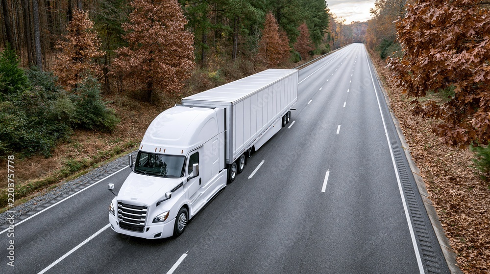 Fototapeta premium white semi truck driving on highway through autumn