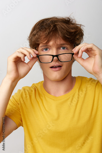 Foto Young man adjusting black glasses with surprise expression