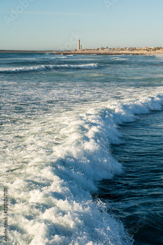 Powerful ocean wave crashing with white foam on coastal beach.