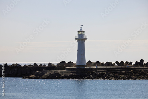 Wollongong's iconic historic Breakwater Lighthouse situated on the Belmore Basin Wollongong Harbour Breakwall. Captured on a bright sunny morning from the Blue Mile walkway shoreline.