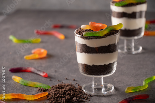 Two individual Halloween chocolate trifles layered with cream and cookie crumbs and topped with colorful gummy worms. Fun spooky party desserts.
