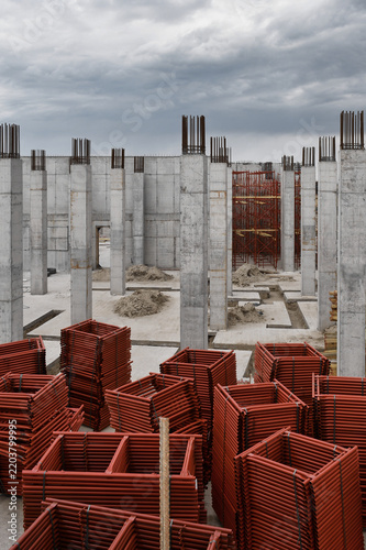 Unfinished concrete building construction site with structural columns and scaffolding
