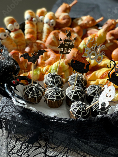 Halloween-themed dessert platter featuring assorted treats including cupcakes with spider web designs, decorated with festive picks