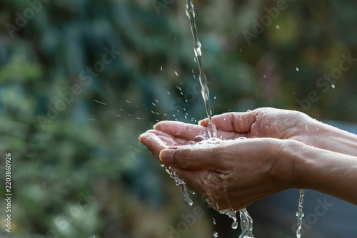 Fotografie Hands Collecting Fresh Flowing Water in Nature