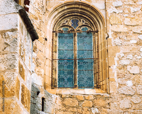 A gothic stone arched window with blue stained glass in an ancient church wall