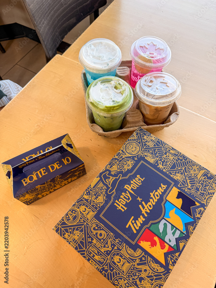 Fototapeta premium Saskachewan, Canada - August 20, 2026: Harry Potter x Tim Hortons limited edition collab drinks and Boite De 10 donut box on wooden table