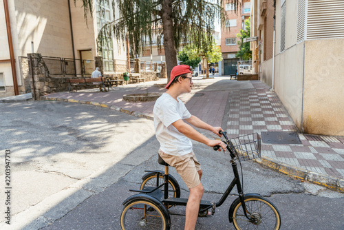 Foto Young cyclist enjoying sunny summer ride on three wheeled bicycle through reside