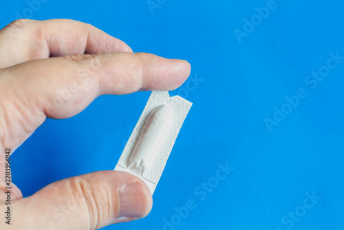 Fotografie Hand Holding Suppository Blister Pack Against Blue Background for Medication and
