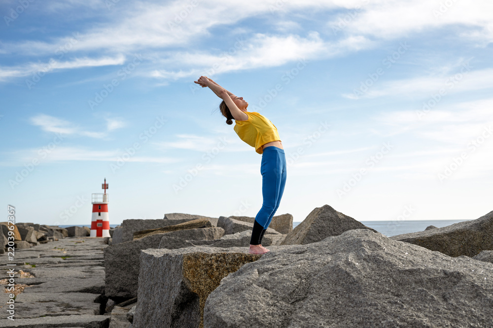 Obraz premium Woman Balancing on Coastal Rocks doing a Yoga Backbend