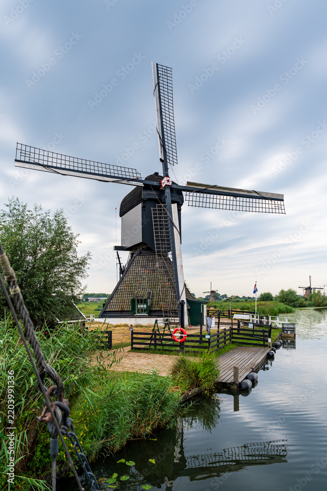 Fototapeta premium Renovated windmill at a river bank in Kinderdijk