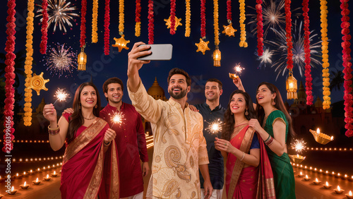 Happy group of young Indian friends taking selfie holding sparklers during Diwali fireworks night