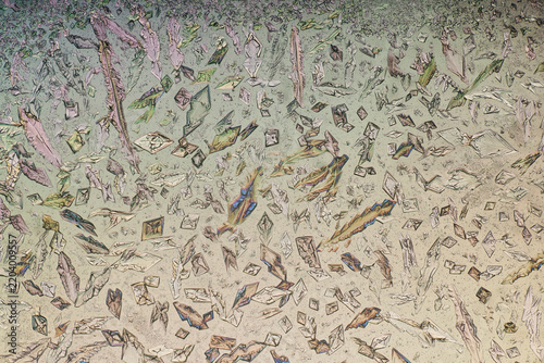 Magnesium sulfate rhomboid and lanceolate crystals under polarized light microscope. Abstract polarized light microscopy background of crystalline mosaic structures on pastel backdrop