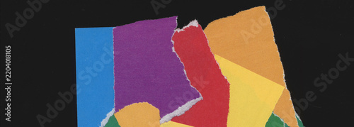 Abstract collage of overlapping blue, purple, red, yellow, orange and green paper pieces with torn edges, irregular blocks and layered rectangular shapes on black background