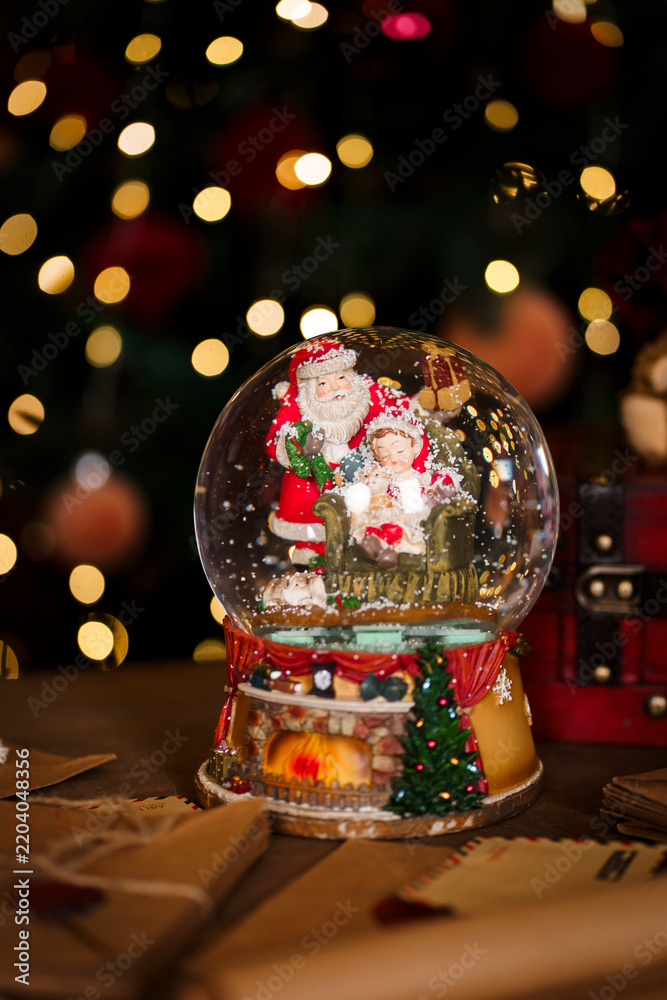 Obraz premium Festive decor with red vintage chest soft toy bear and musical snow globe near Christmas tree
