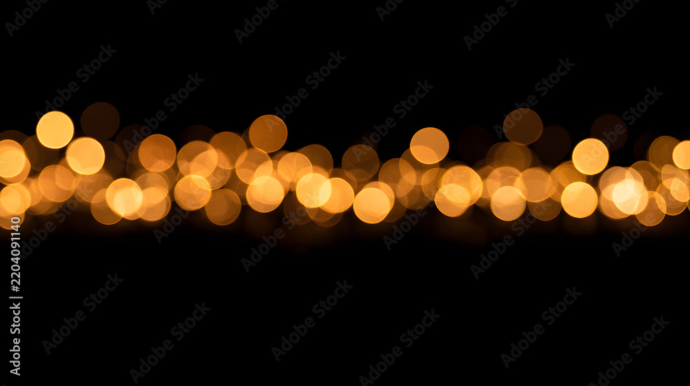 Obraz premium A black background with golden bokeh lights in a horizontal band.