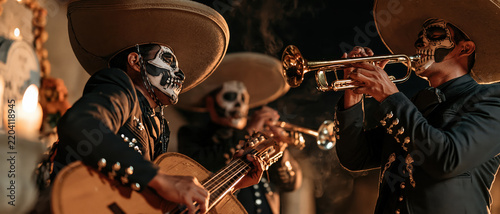 Atmospheric Dia de los Muertos celebration featuring mariachi musicians in sombrero hats, sugar skull makeup, playing trumpet and guitar by candlelight. Ideal for cultural, festival, and.