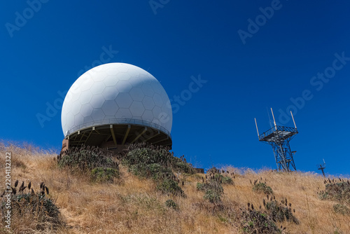 Large radar dome and communication antennas on Pico Arieiro, in Madeira, Portugal, under a clear, deep blue sky.