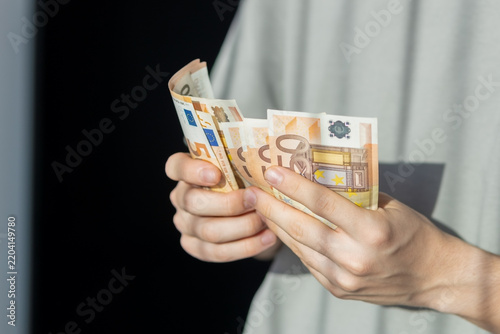 Hands counting euro banknotes in foreground