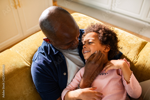 Man cuddling child on sofa at home