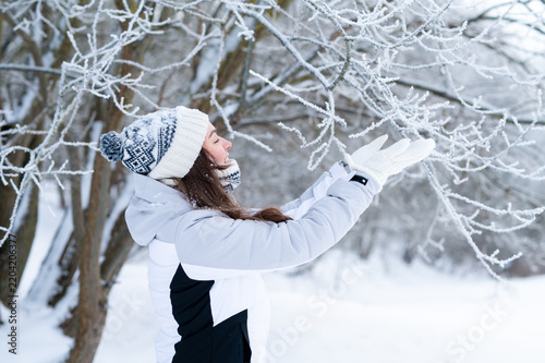 Woman touching snowy tree branches outdoors in winter park