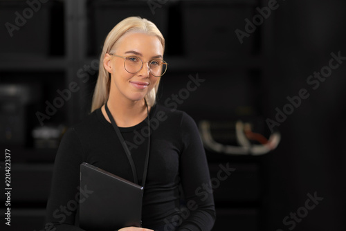 Professional female IT consultant with tablet in a dark studio, ready for tech and cybersecurity topics