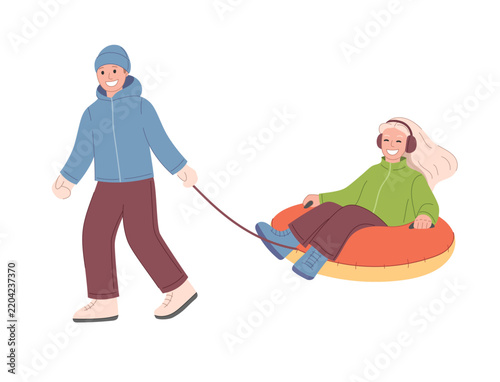 Snow tubing winter activity. Boy pulling girl on an inflatable snow tube.