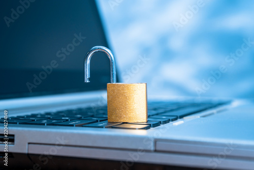 An unlocked lock is lying on the laptop keyboard.