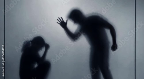 Silhouettes of an adult looming over a cowering child behind frosted glass, conveying intimidation, fear, and emotional distress