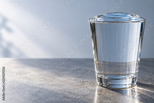 Clear glass filled to the brim with water. Space for text.