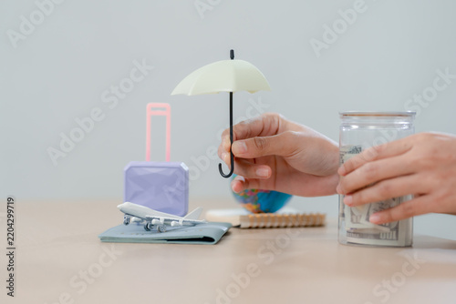 Foto Travel insurance concept with hands holding a small umbrella over a toy airplane