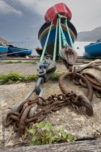 Boat mooring with pulleys and rusty chain in scilla harbour, Italy