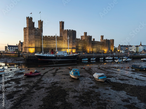 Caernarfon castle at evening with boats moored in welsh harbor