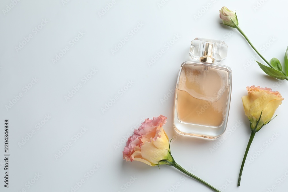 Fototapeta premium Bottle of perfume and flowers on white background, flat lay. Space for text