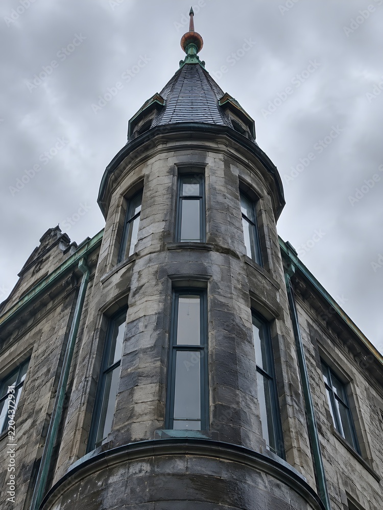 Fototapeta premium Slate-clad corner turret with a copper finial and narrow windows
